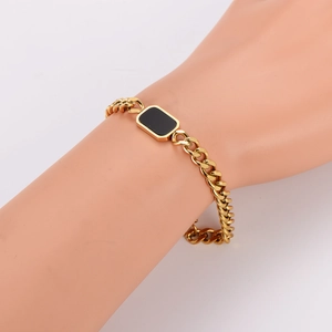 Gold Cuban chain bracelet with black rectangular shell inlay on mannequin wrist