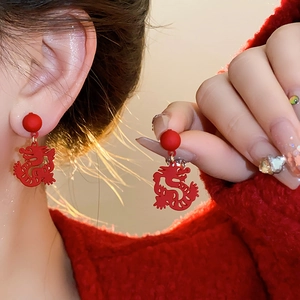 Detail of red dragon-shaped drop earrings with matte finish and matching red bead stud