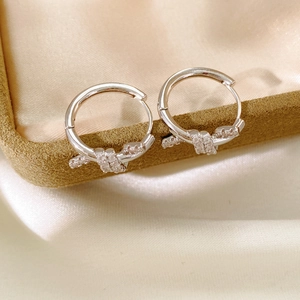 Close-up of silver knot hoop earrings with pave cubic zirconia on silk fabric