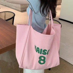 Detail of pink canvas tote bag showing the soft texture and green MAISON 8 printed lettering