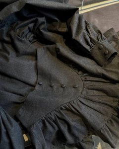 Detailed close-up of black plaid fabric with ruffled edges and single-breasted button design