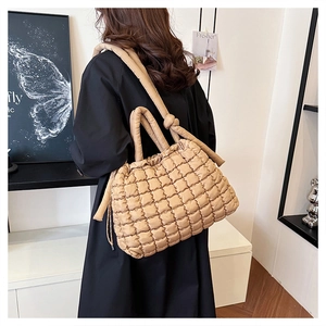 Rear view of khaki quilted tote bag worn by a model in a minimalist indoor setting