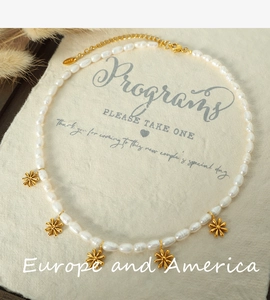 Detail of freshwater pearl necklace with five golden daisy flower pendants on linen