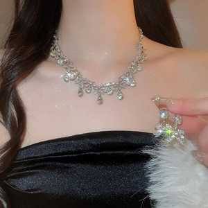Close-up of elegant silver necklace set with rhinestone bow and teardrop pendant on model