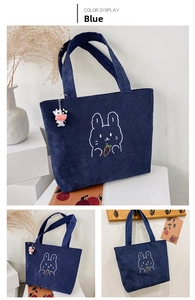 Detail of blue corduroy tote bag featuring rabbit embroidery and a cow charm accessory