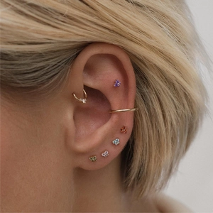 Detailed view of colorful zircon flower ear studs and gold cuffs on a model ear