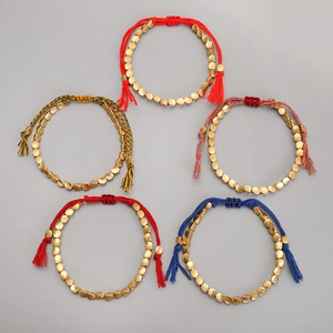 Detalle de cinco pulseras tejidas a mano con cuentas de latón y cierres de borlas