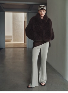 Detail of dark brown faux fox fur cashmere jacket paired with gray flared trousers