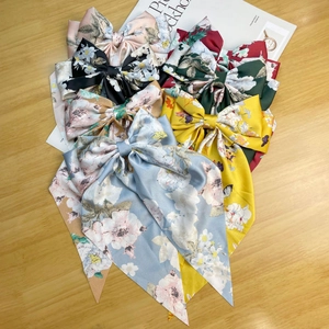 Flat lay of multiple satin bow hair clips in various colors on a wooden surface