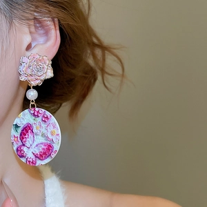 Detail of acrylic floral earring with embossed butterfly and rose in retro style