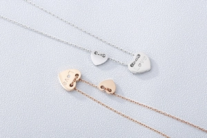 Detail von Doppelherz-Anhängern mit Love-Gravur und kleinem Kristall in Silber und Roségold