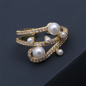 Détail de bague dorée à double rangée avec perles blanches et zircons incrustés
