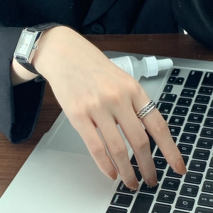 Minimalist silver braided ring and rectangular watch worn while using a laptop