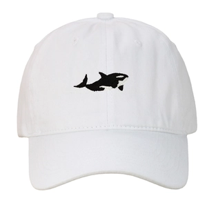 Close-up of a white cotton baseball cap featuring detailed black orca whale embroidery