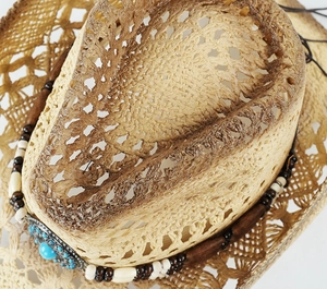 Detailed close-up of woven straw texture and ethnic beaded band on cowboy hat