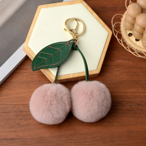 Detail of pink faux rabbit fur cherry keychain with green leather leaves and gold clip