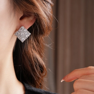 Gros plan de boucles d'oreilles carrées en argent avec zircons portées par un mannequin
