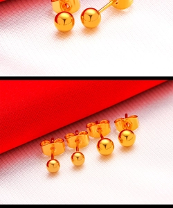 Macro shot of two pairs of round gold-plated stud earrings with polished metallic finish