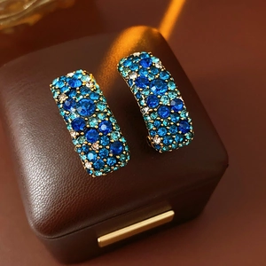 Détail macro de boucles d'oreilles bohèmes rectangulaires aux cristaux bleus