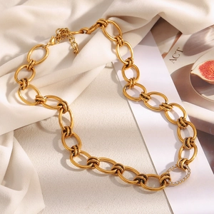 Macro shot of a chunky gold plated chain necklace with a sparkling cubic zirconia ring link