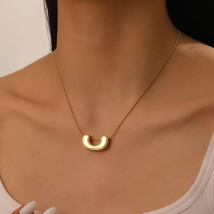 Close-up of gold plated stainless steel U-shaped pendant necklace worn by a female model