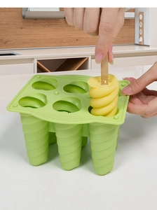 Détail du retrait d'une glace en spirale jaune du moule en silicone vert à 6 trous