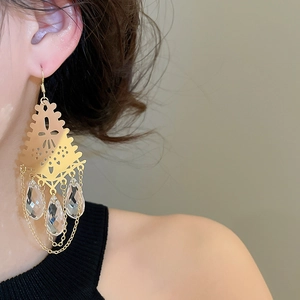 Close-up of French vintage hollow gold earrings with crystal teardrop tassels on a model