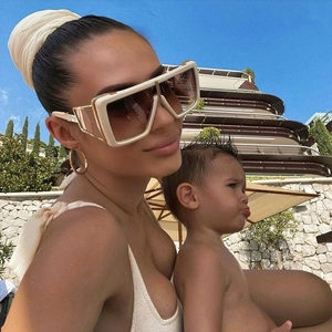 Close-up of white chunky sunglasses with gold accents and brown gradient lenses