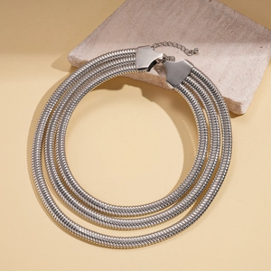 Detailed view of silver triple-layered snake bone chain necklaces on textured stone