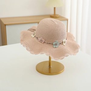 Détail d'un chapeau de paille rose avec fleurs 3D et bordure en dentelle ondulée