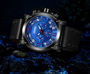 Detail of blue dial chronograph watch with leather strap on illuminated dark stones