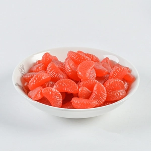 Macro shot of realistic 2cm miniature PVC orange slices in a white floral ceramic bowl