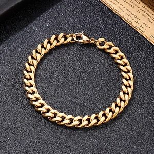 Detail of golden stainless steel Cuban link bracelet with lobster clasp on black background