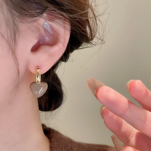 Détail de la boucle d'oreille cœur vintage avec finition ambrée portée par le modèle