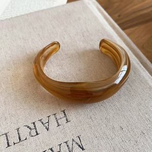 Detailed macro view of amber resin open cuff bracelet with marble texture on vintage book