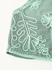Détail de robe de vacances verte avec broderie de feuilles délicates et bords festonnés