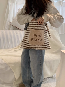 Detail of fuzzy striped tote bag with plush FUN PIACE pocket and warm texture