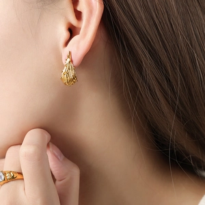 Gouden onregelmatige druppeloorbellen met organische textuur, getoond op een model, luxe