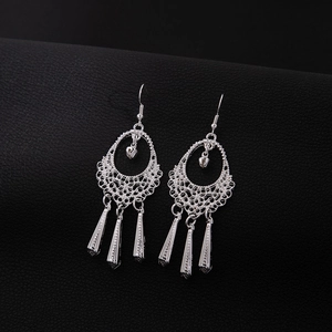 Macro shot of silver-colored hollow ethnic earrings with leaf fringe on black background