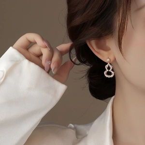 Close-up of elegant gold hollow gourd earrings with diamonds on a model's ear