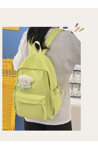 Detail view of the bright green nylon backpack with front pocket and white floral pendant