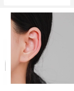 Close-up of a silver hollow heart-shaped ear cuff worn on the upper ear cartilage