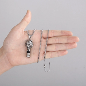 Detailed view of a silver lion head whistle pendant made of durable titanium steel
