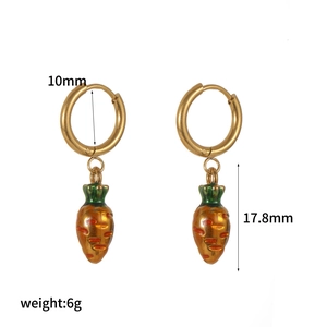 Detail of golden stainless steel hoop earrings featuring small carrot pendants with enamel
