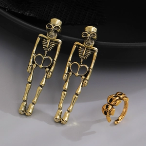 Detailed view of antique gold skull earrings and matching multi-skull ring on black lace