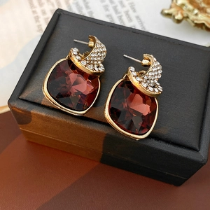 Macro detail of vintage square red gemstone earrings with gold diamond-set accents