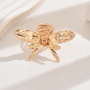 Macro shot of golden liquid metal butterfly hair claw clip with detailed spring mechanism