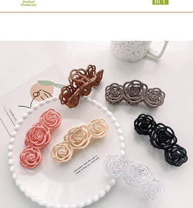 Detail view of hollow camellia flower hair claws in six matte colors on white plate