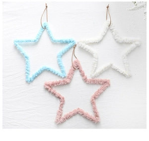 Detailed view of plush star ornaments in soft blue, pink, and beige with fuzzy texture
