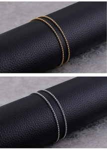 Detailed view of woven stainless steel chains in gold and silver on black leather stand